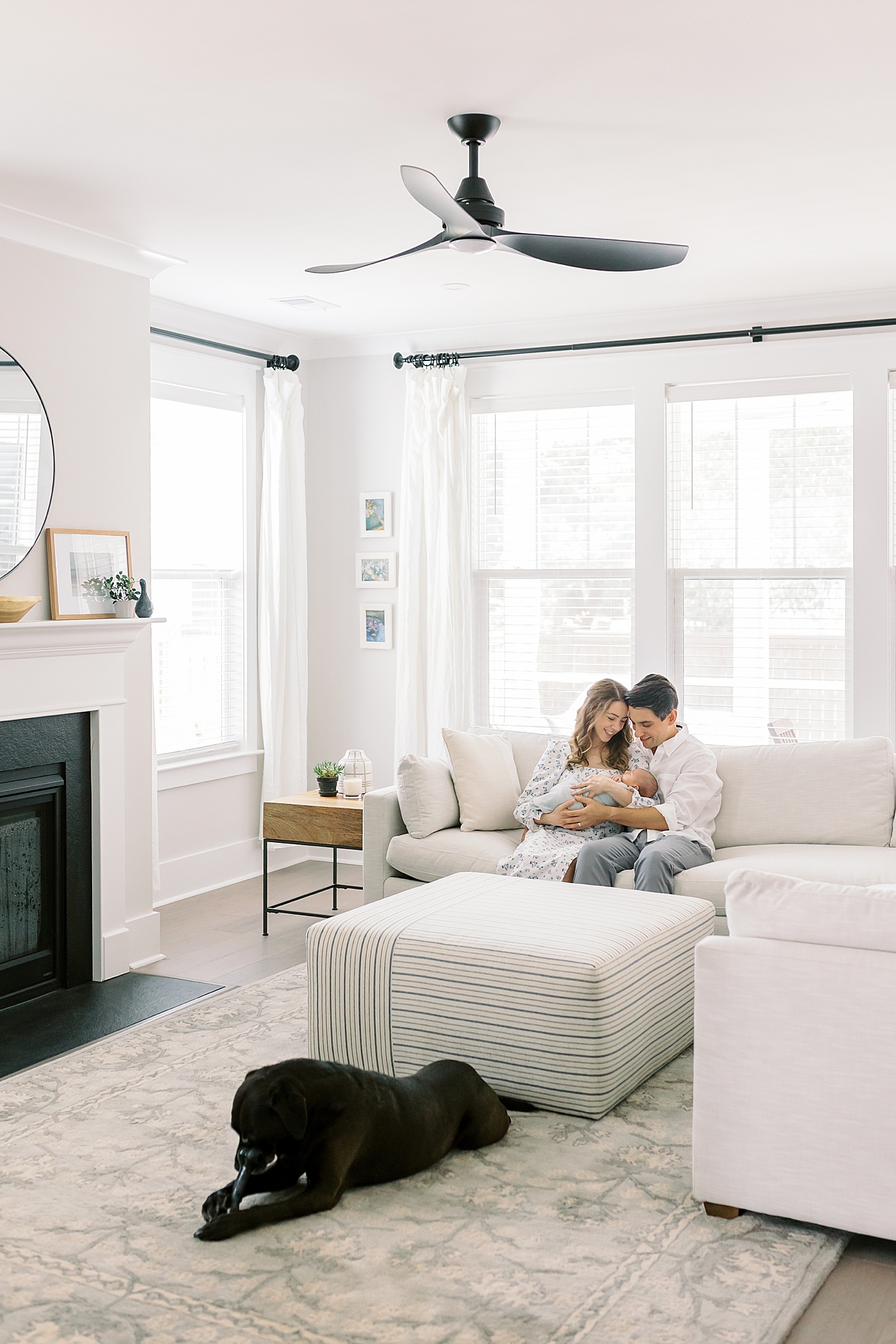 Mom and dad in their living room holding their baby during lifestyle newborn photos | Image by Caitlyn Motycka