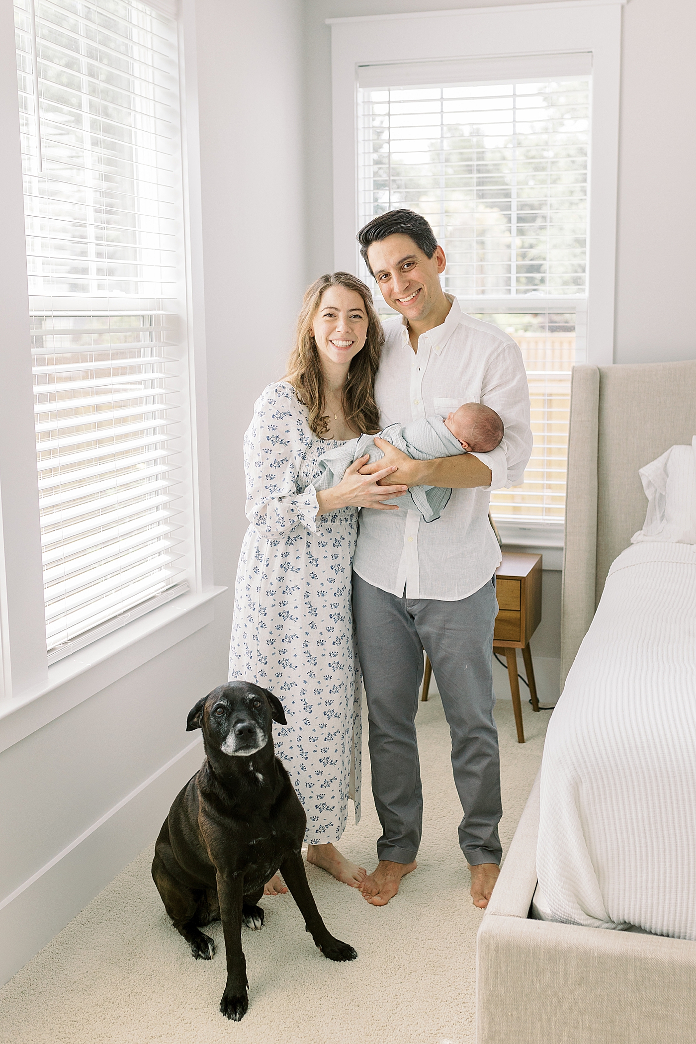 Mom and dad holding their new baby in their bedroom during lifestyle newborn photos | Image by Caitlyn Motycka
