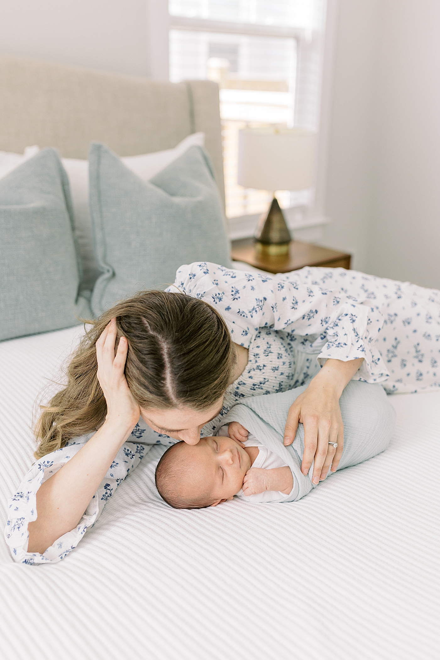 Mom kissing her new baby during lifestyle newborn photos | Image by Caitlyn Motycka