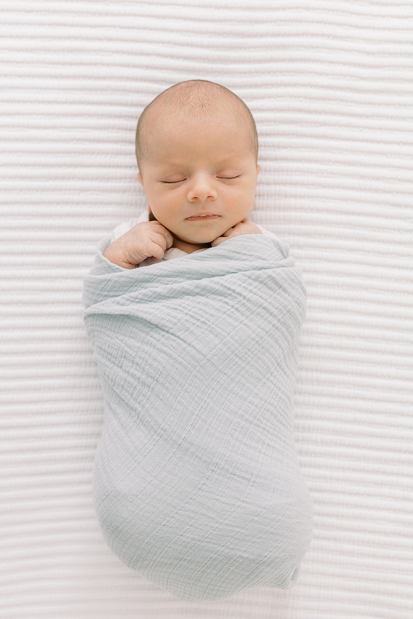 Sleeping newborn baby boy wrapped in a blue swaddle | Image by Caitlyn Motycka