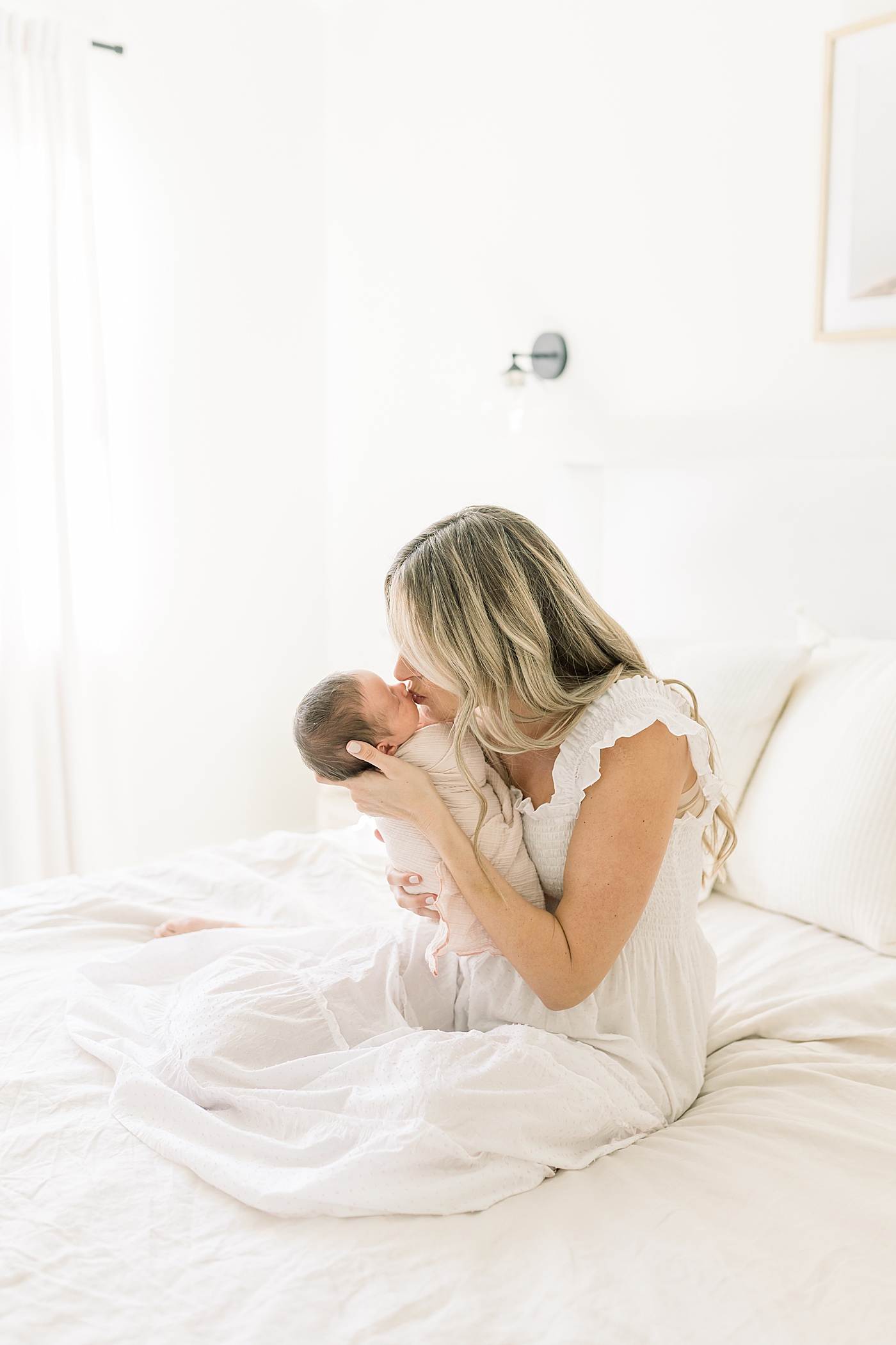 Mom kissing her newborn baby girl | Image by Caitlyn Motycka