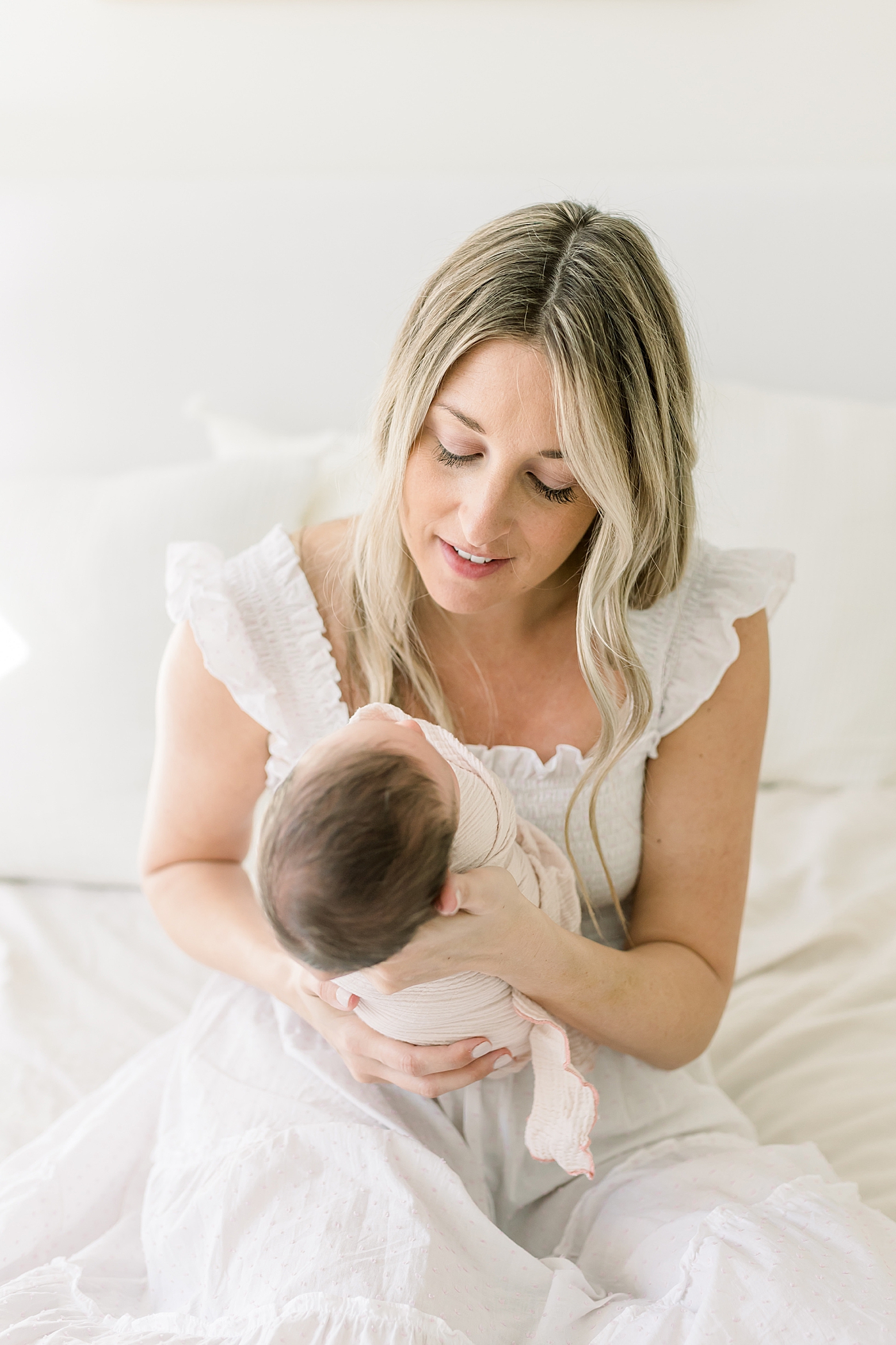 Detail of mom in white dress holding her newborn baby girl | Image by Caitlyn Motycka