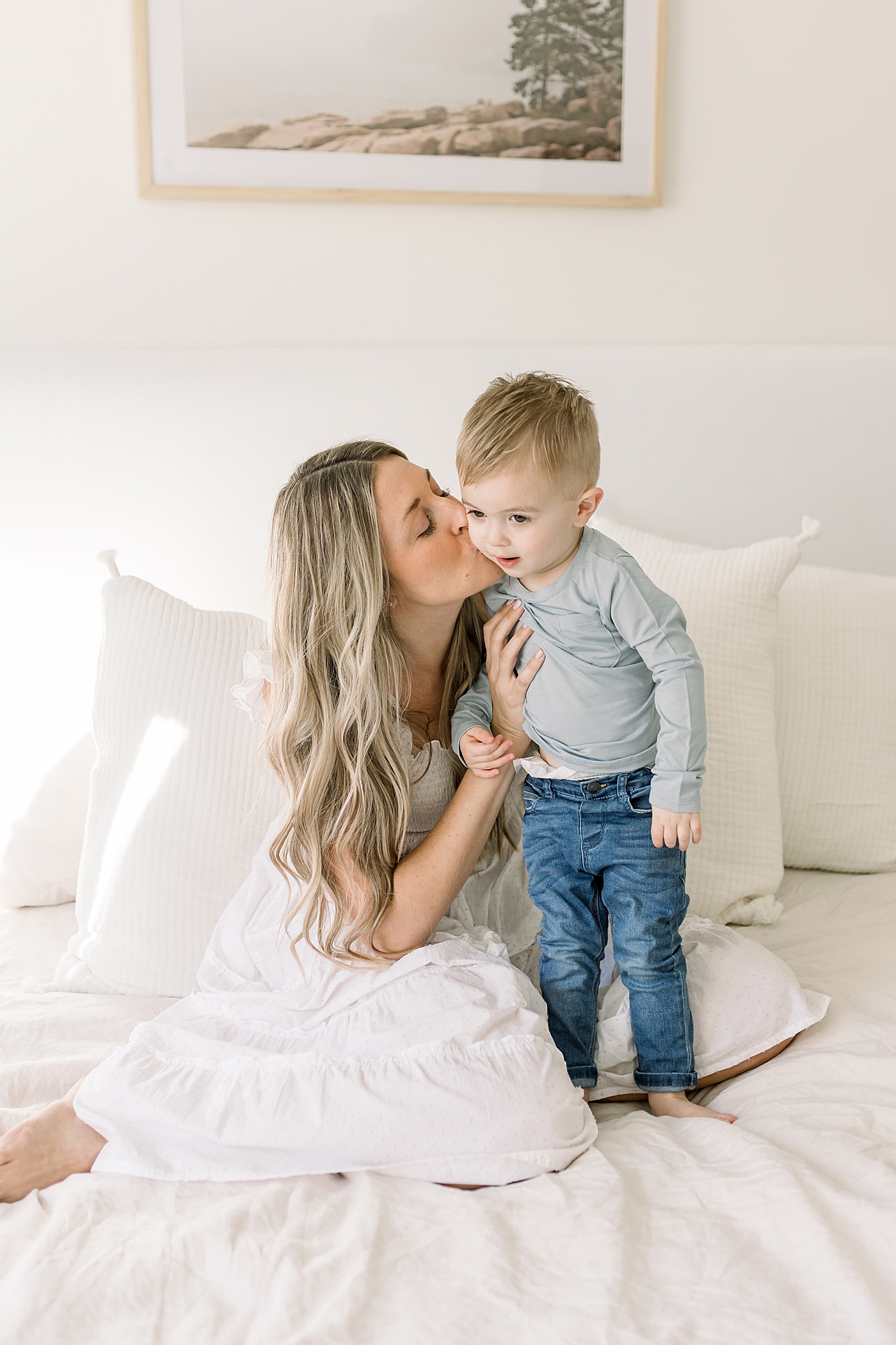 Mom in white dress kissing her toffler boy on the cheek | Newborn Photos with Toddler with Caitlyn Motycka Photography