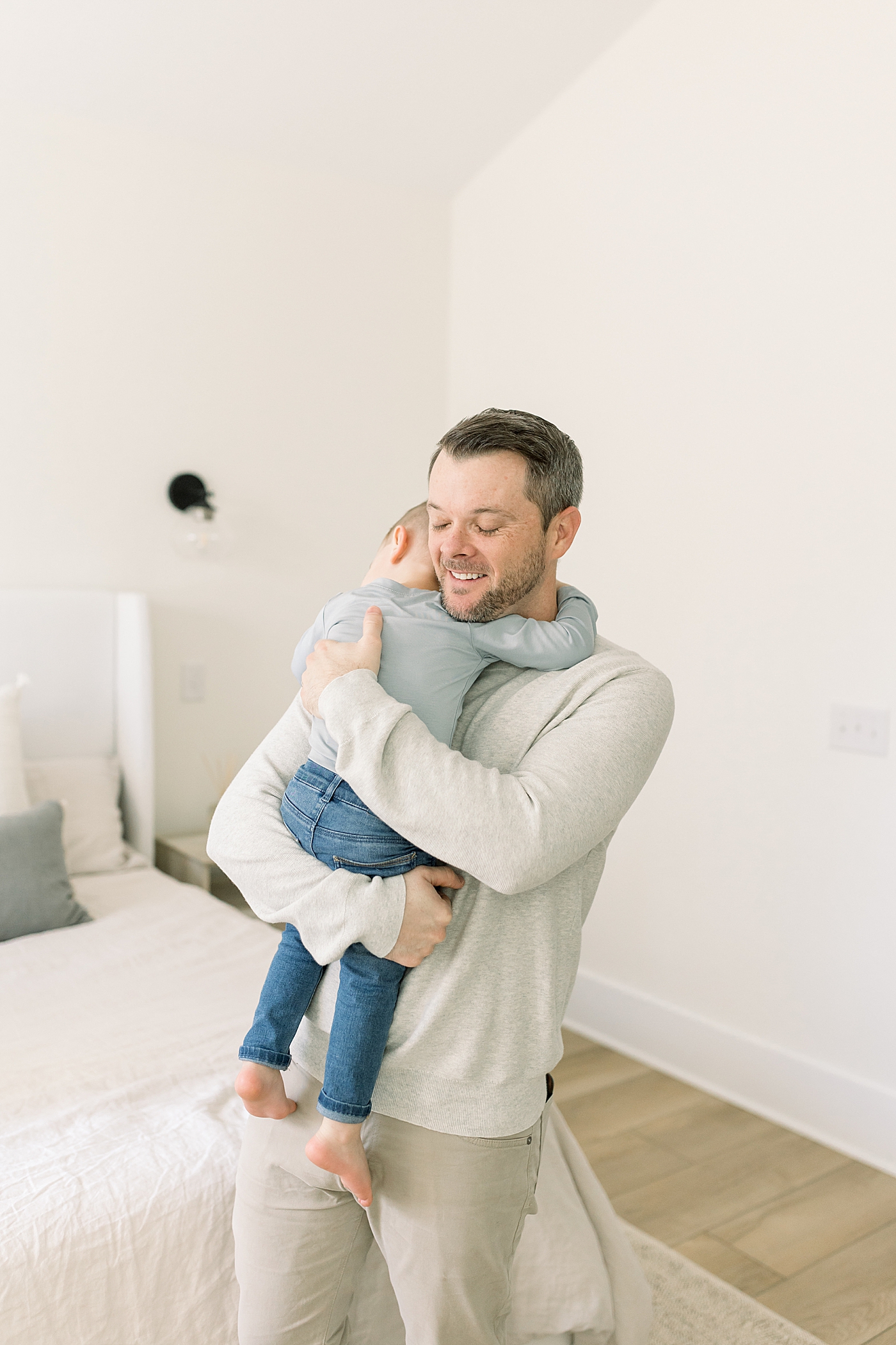 Dad in neutral colors holding and hugging his toddler boy | Newborn Photos with Toddler with Caitlyn Motycka Photography