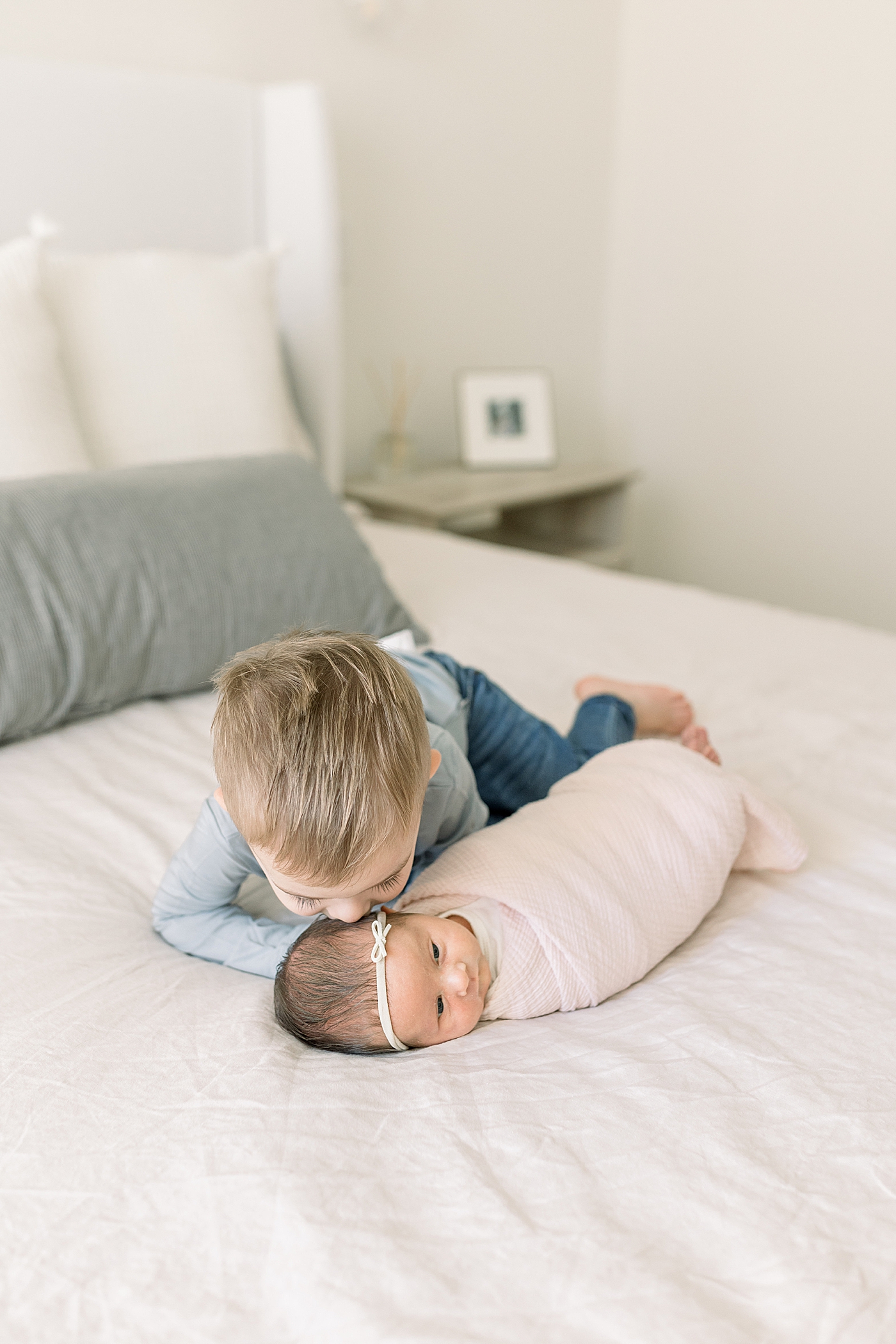 Toddler boy kissing his new baby sister | Image by Caitlyn Motycka