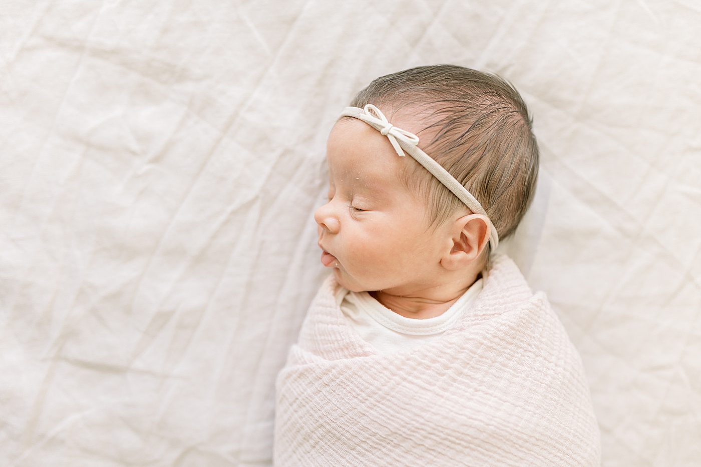 Sleeping newborn baby girl in a white blanket | Image by Caitlyn Motycka
