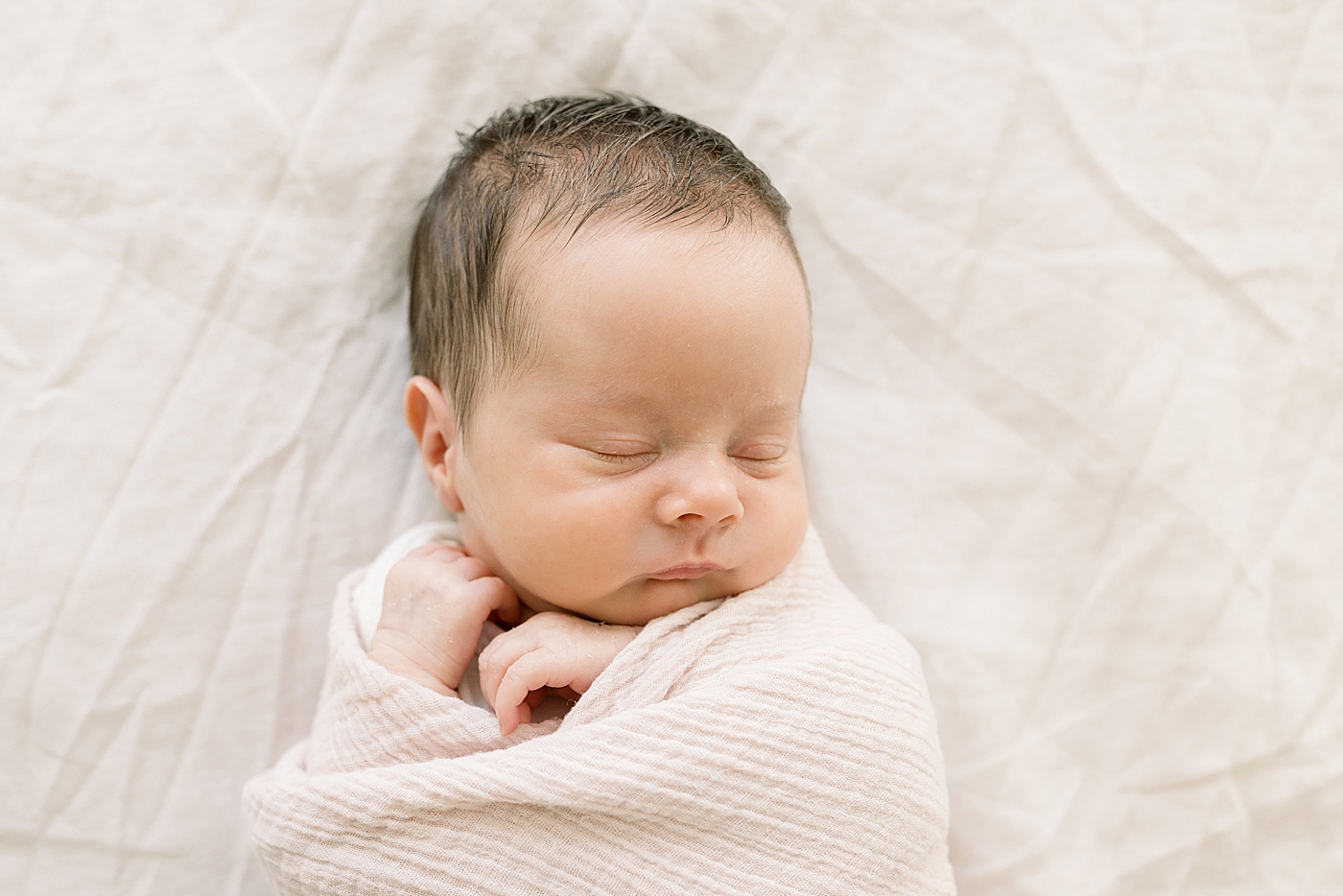 Sleeping newborn baby girl in a cream blanket | Image by Caitlyn Motycka