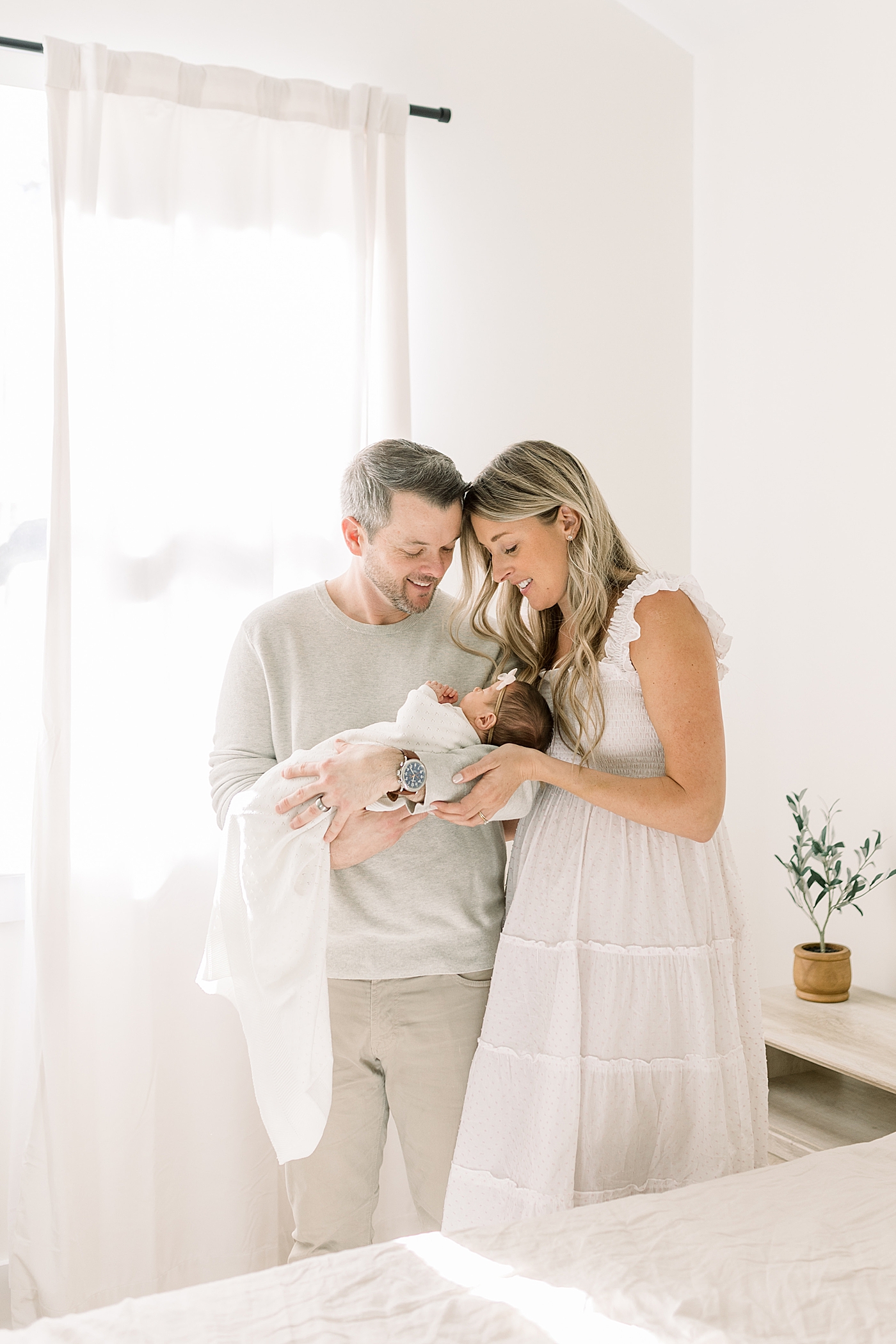 Mom and dad holding their newborn in their bedroom | Image by Caitlyn Motycka