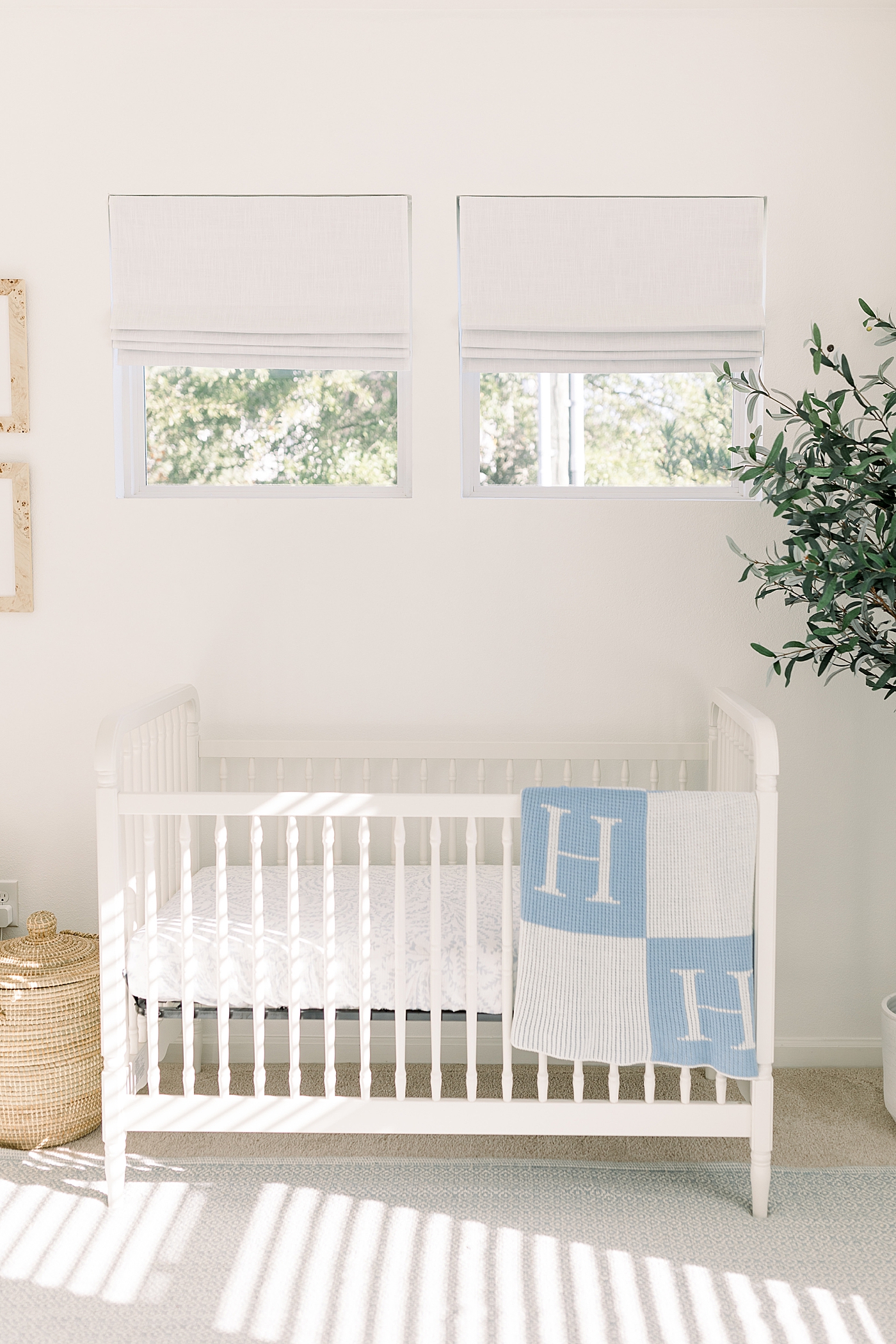 White crib in a baby room with white walls and a white carpet during baby boy newborn session | Image by Caitlyn Motycka Photography