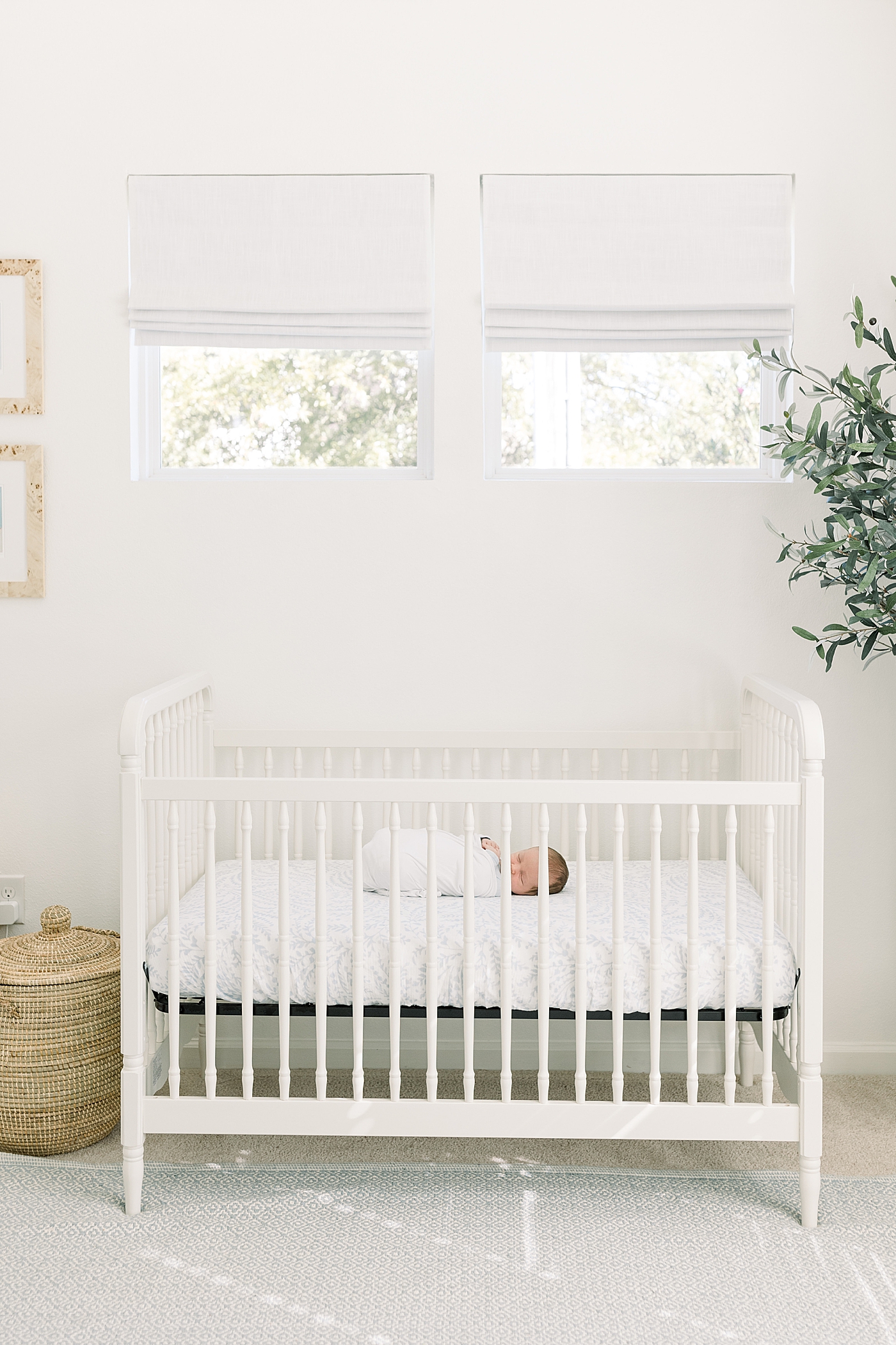 Baby swaddled in a white crib in a white room with natural light | Image by Caitlyn Motycka Photography