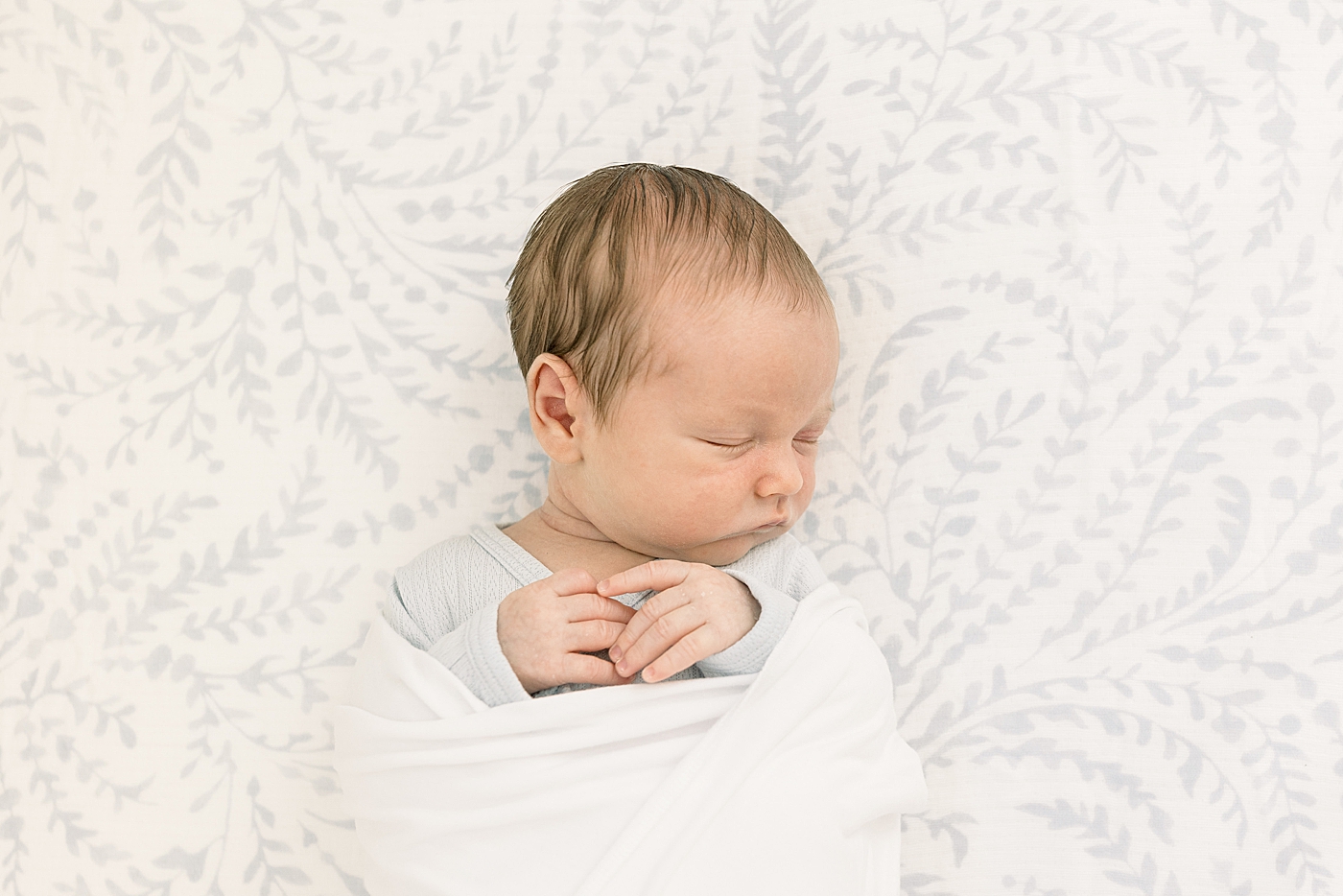Close up of a newborn swaddled in a white crib | Image by Caitlyn Motycka Photography