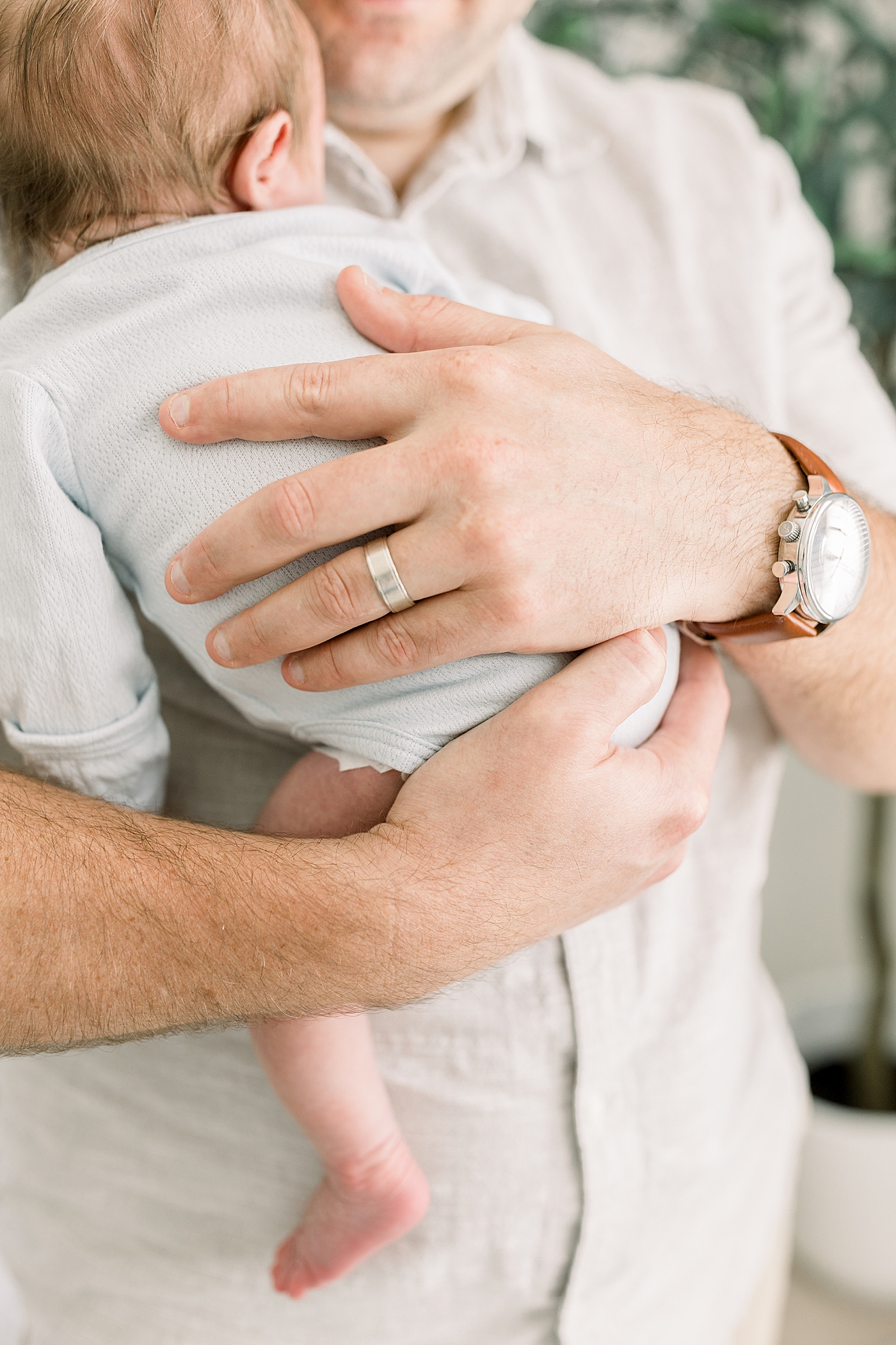 Close up of a newborn in his dad's arms during baby boy newborn session | Image by Caitlyn Motycka Photography