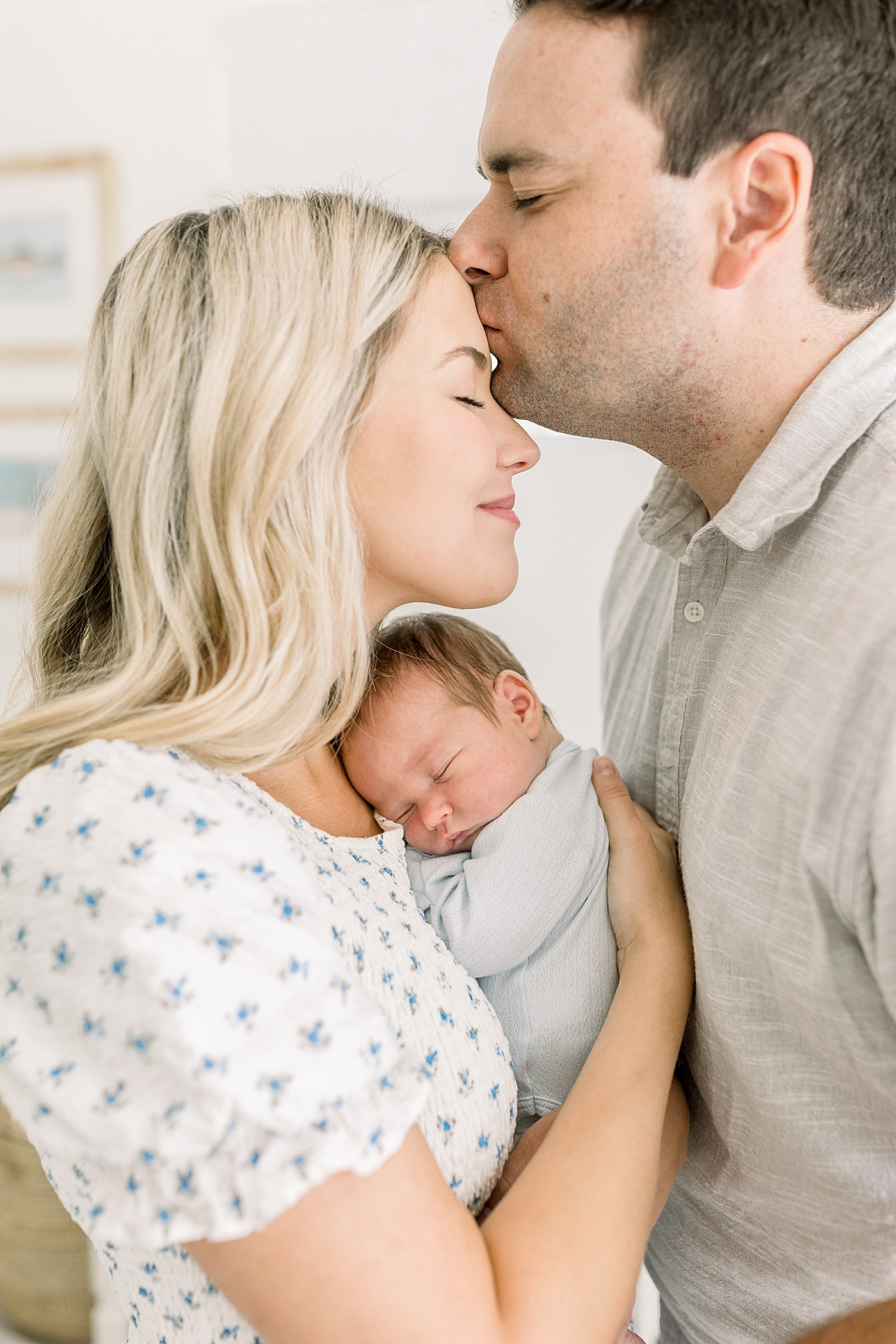 Close up of a newborn in his mother's arms with dad kissing the mom on the forehead | Image by Caitlyn Motycka Photography