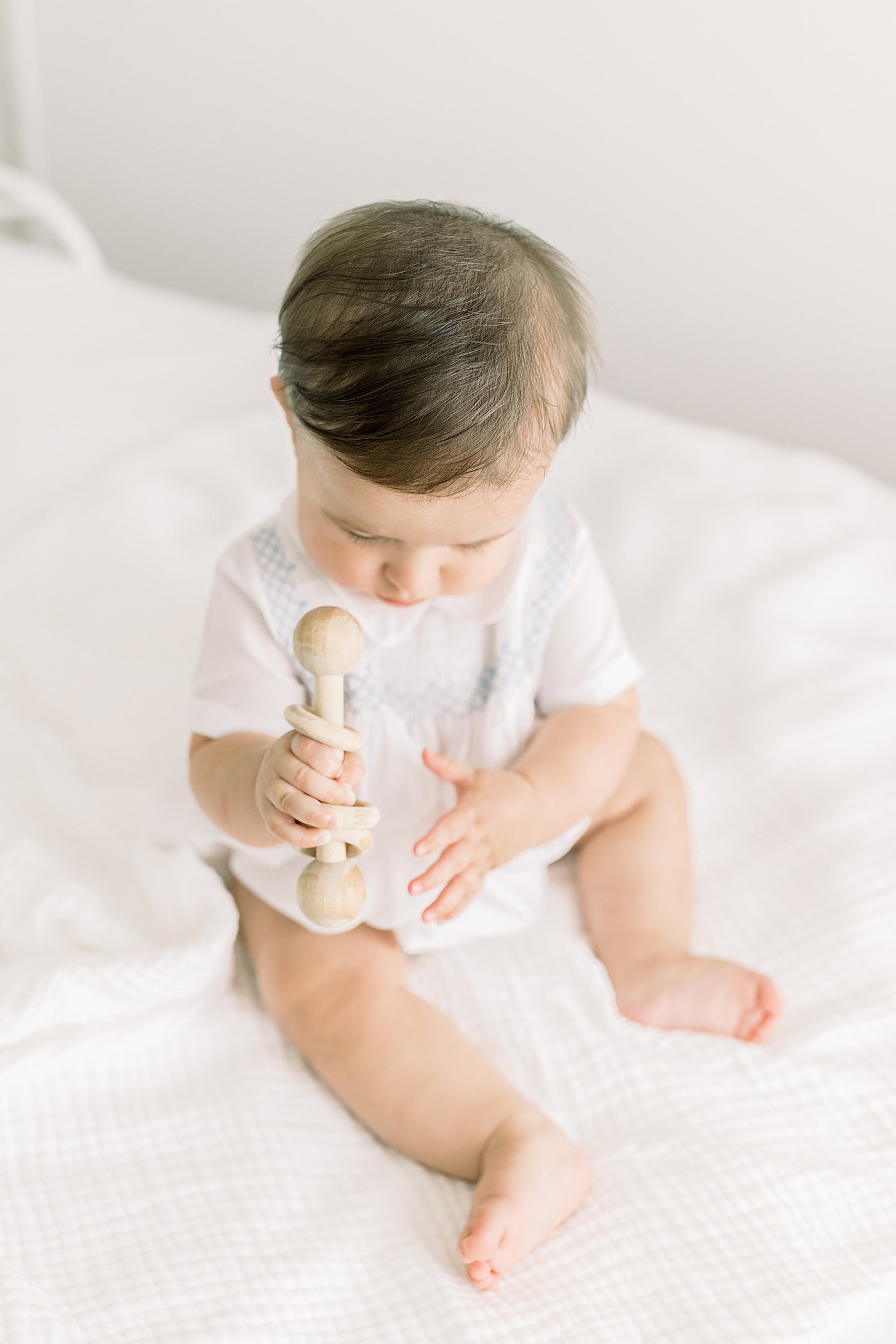 Baby playing with a wooden toy in a softly lit room | Images by Caitlyn Motycka