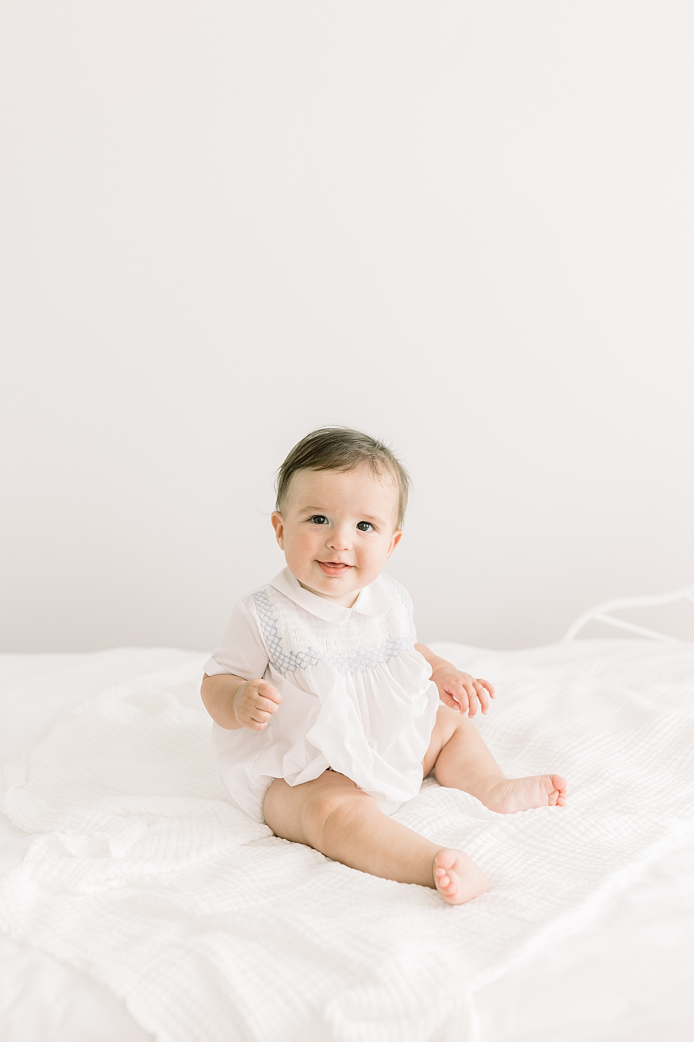 Baby sitting up and looking at the camera in a softly lit room during Studio Milestone Session | Images by Caitlyn Motycka