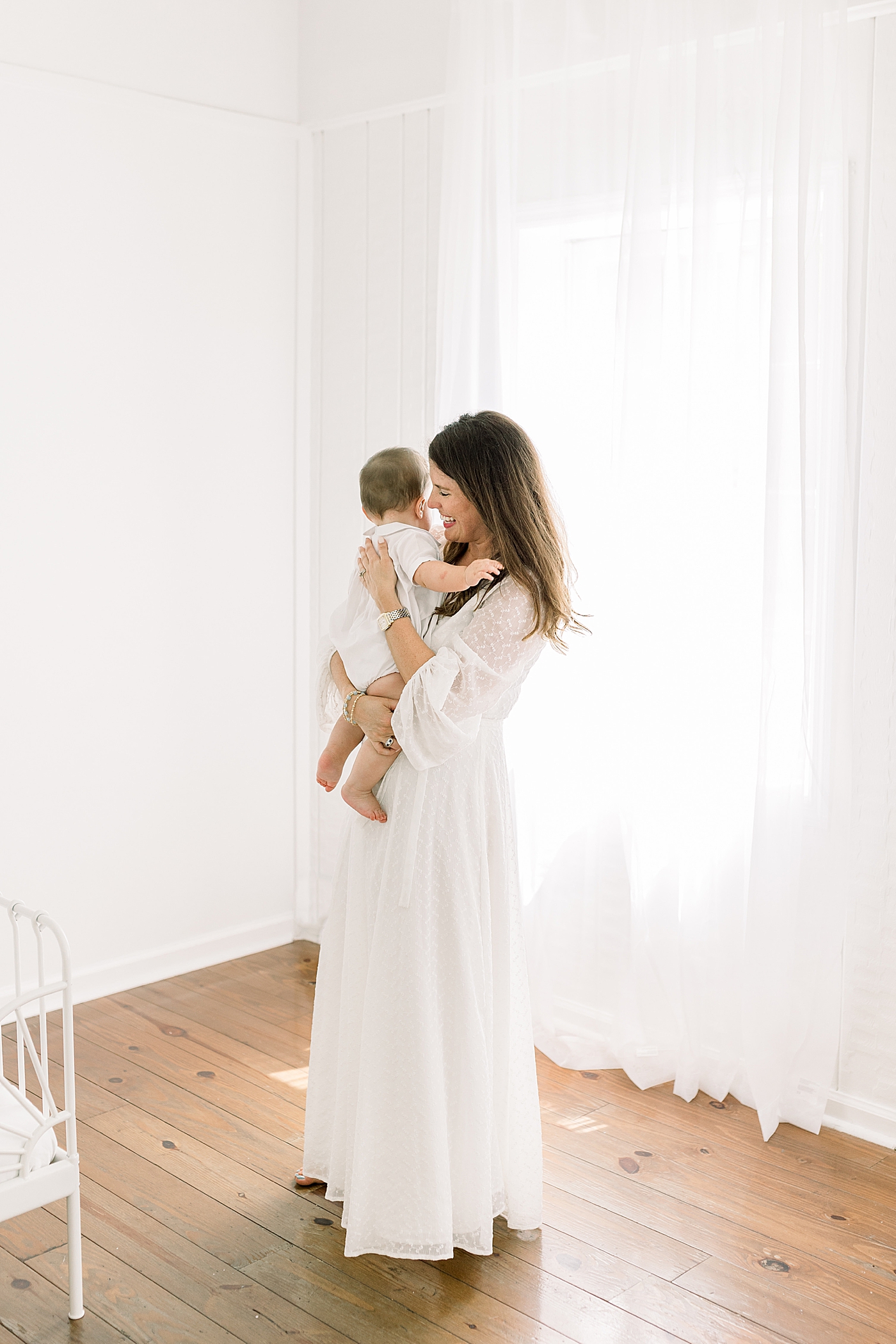 Mother standing up and holding her baby in a softly lit room during Studio Milestone Session | Images by Caitlyn Motycka