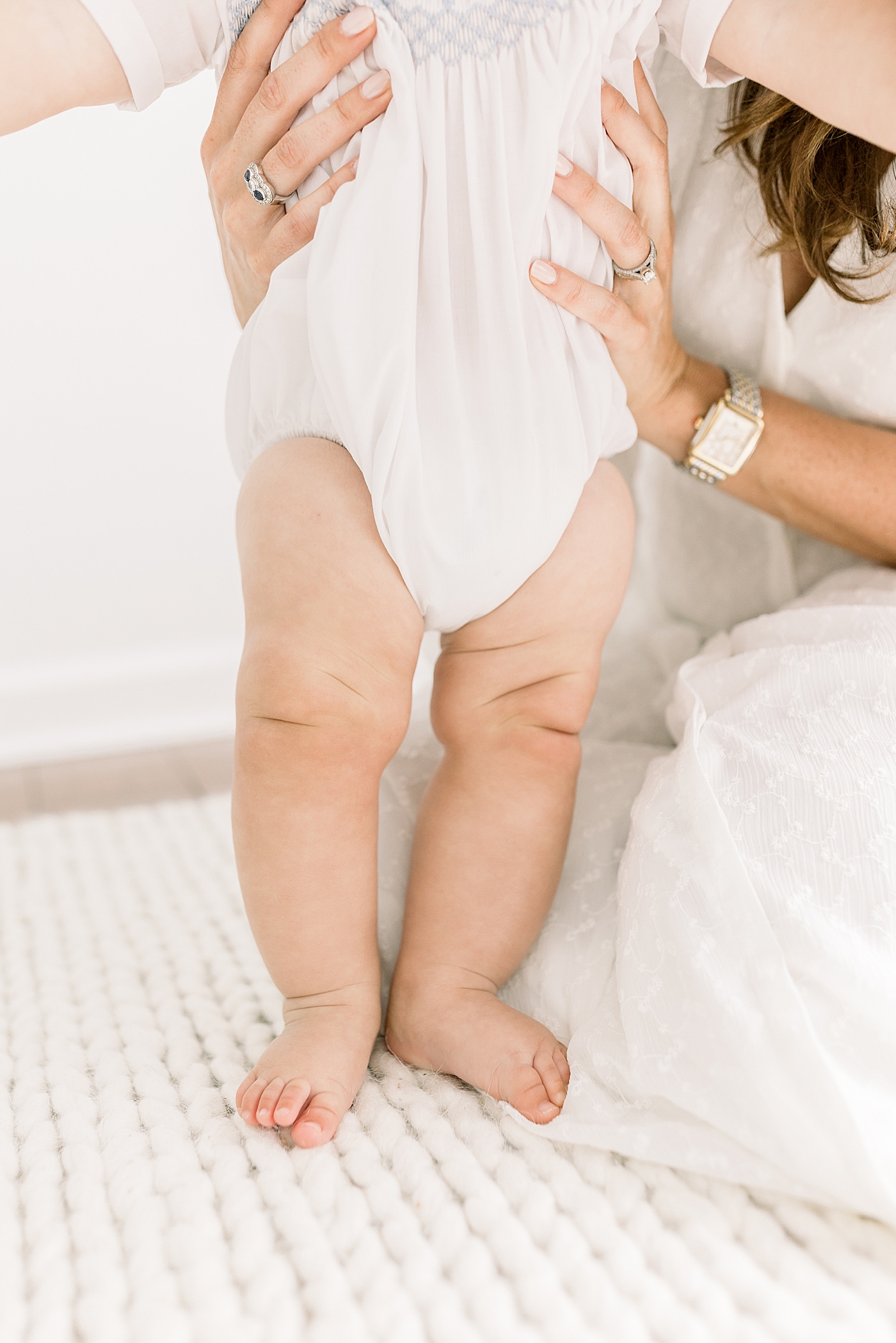 Close up of mother kneeling and holding baby in a white room with a white rug | Images by Caitlyn Motycka
