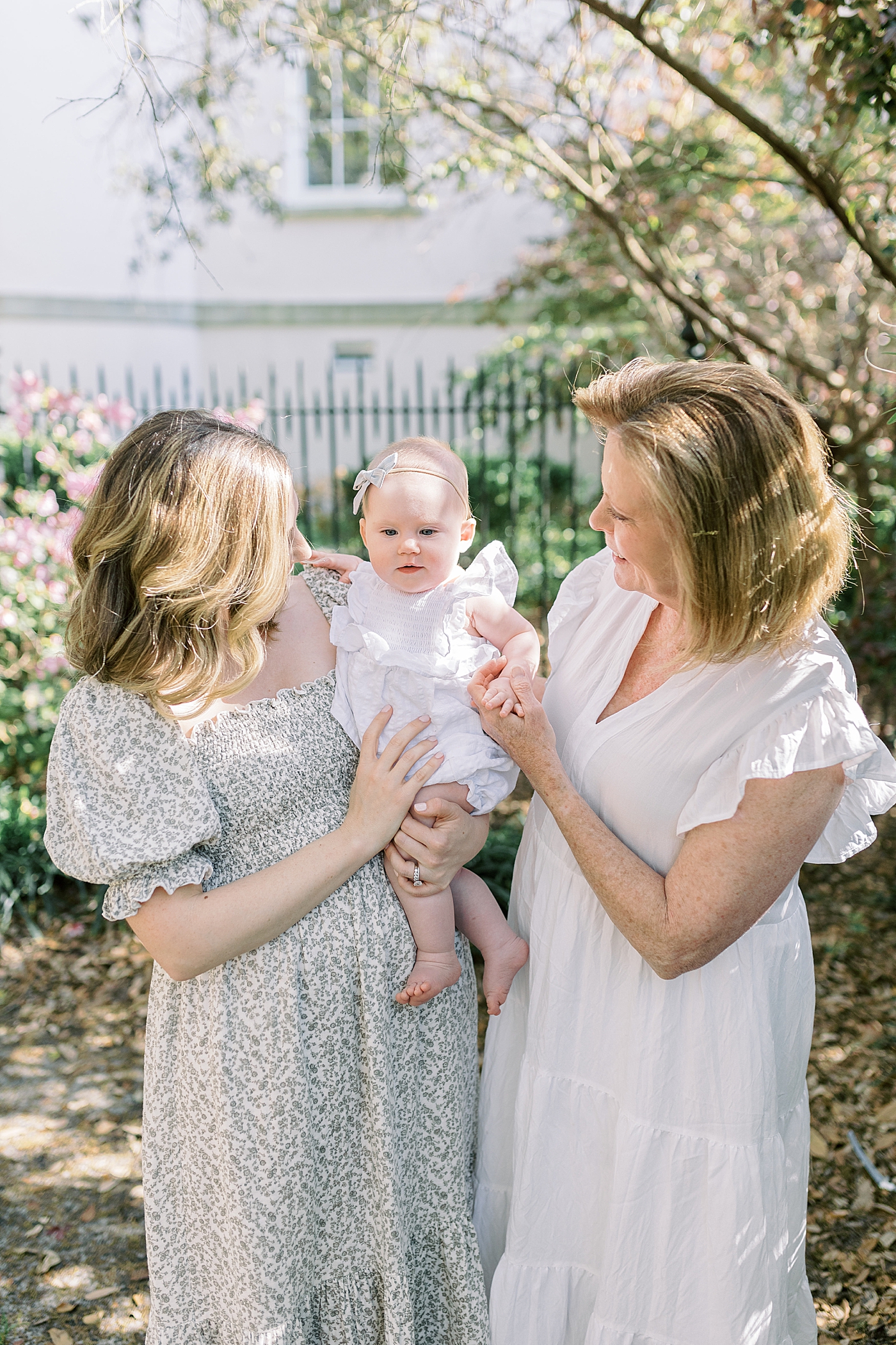 Mother and grandmother in spring dresses holding and admiring baby | Image by Caitlyn Motycka