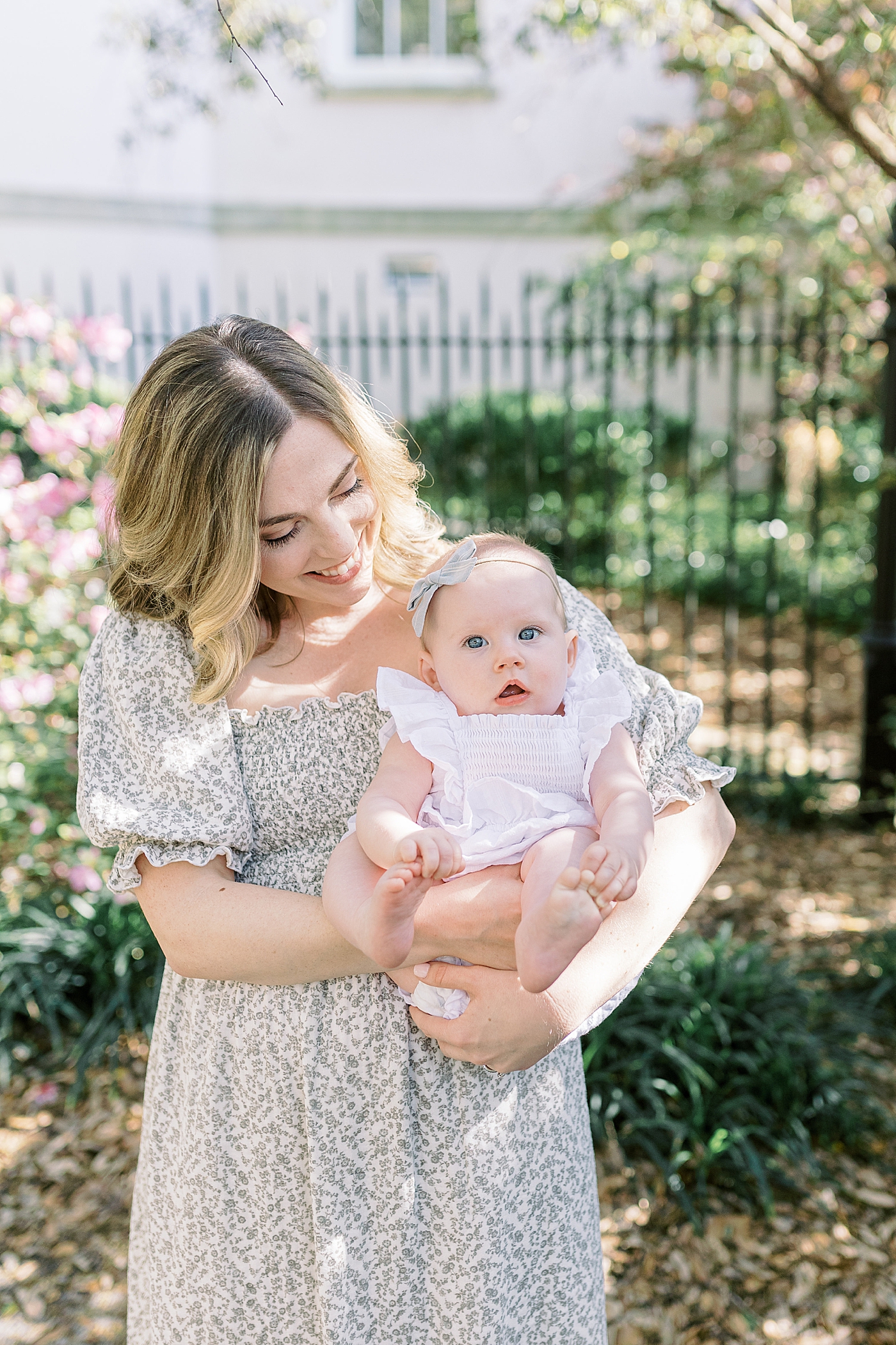 Close up of mother in a spring dress holding her baby during Spring Motherhood Minis in Charleston | Image by Caitlyn Motycka