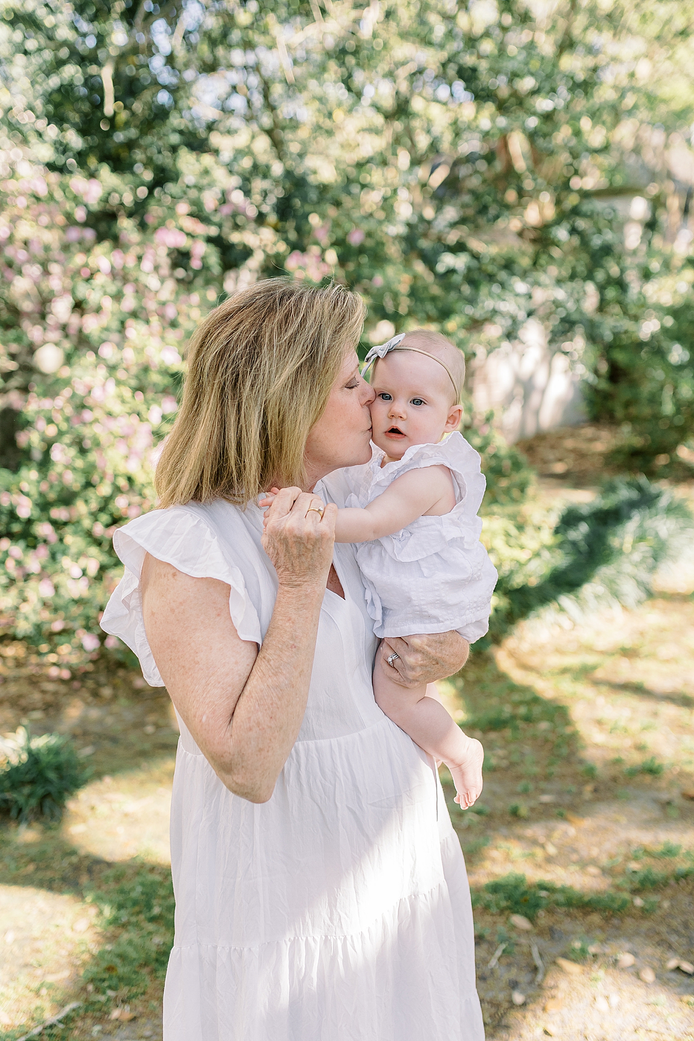 Grandmother kissing and holding her grandchild during Spring Motherhood Minis in Charleston | Image by Caitlyn Motycka