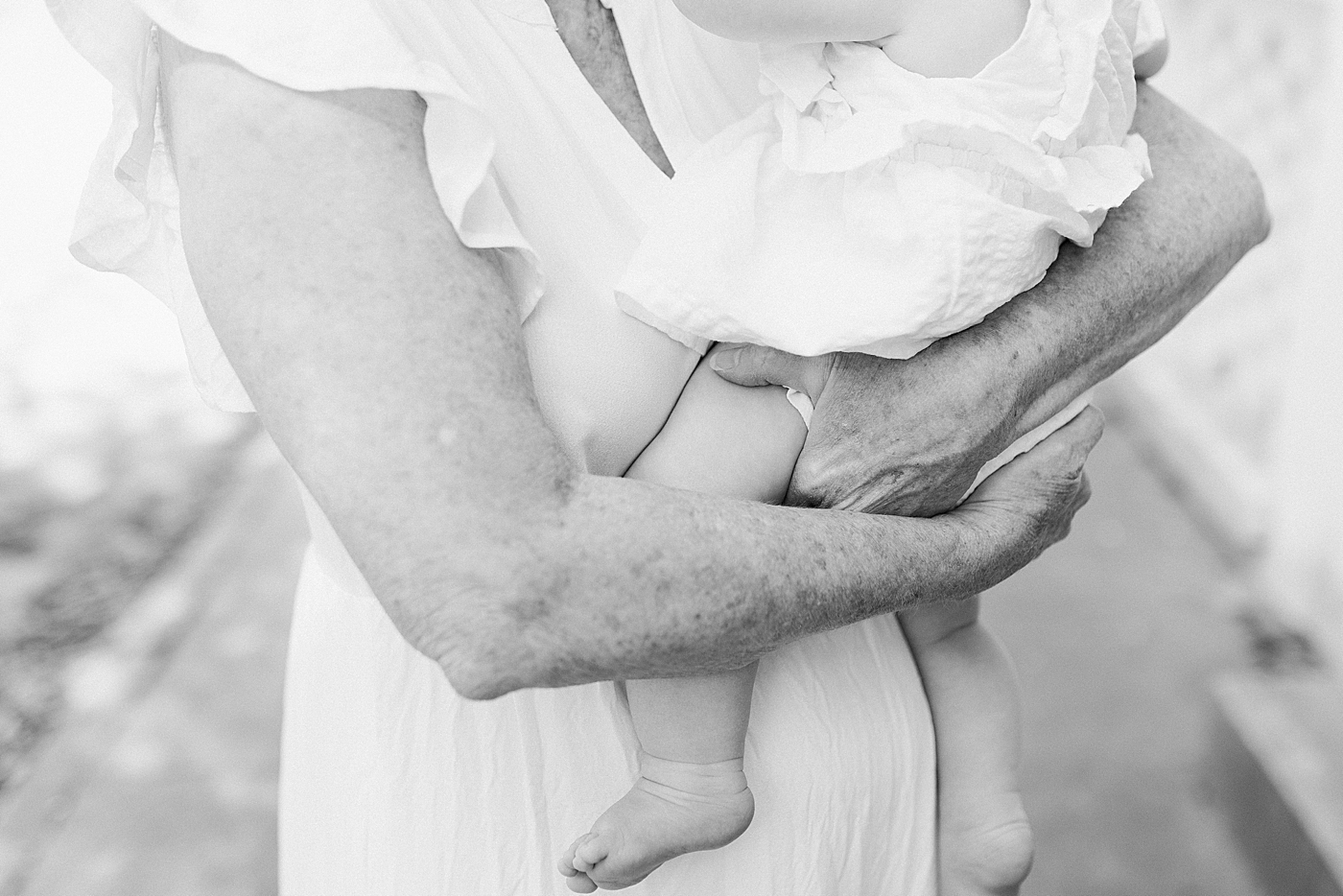 Black and white image of a grandchild in her grandmother's arms | Image by Caitlyn Motycka