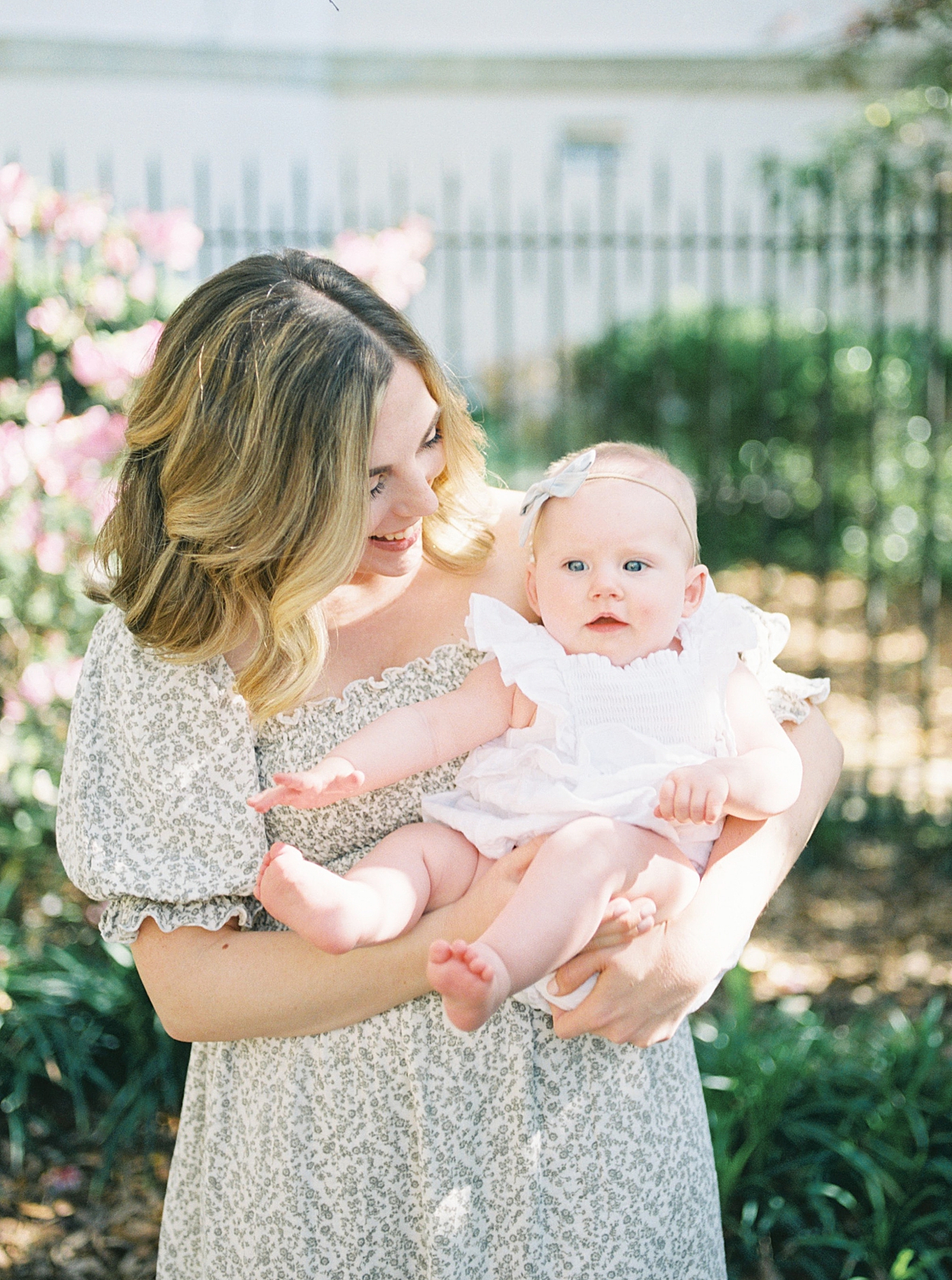 Mother in a spring dress holding and smiling at her baby | Image by Caitlyn Motycka