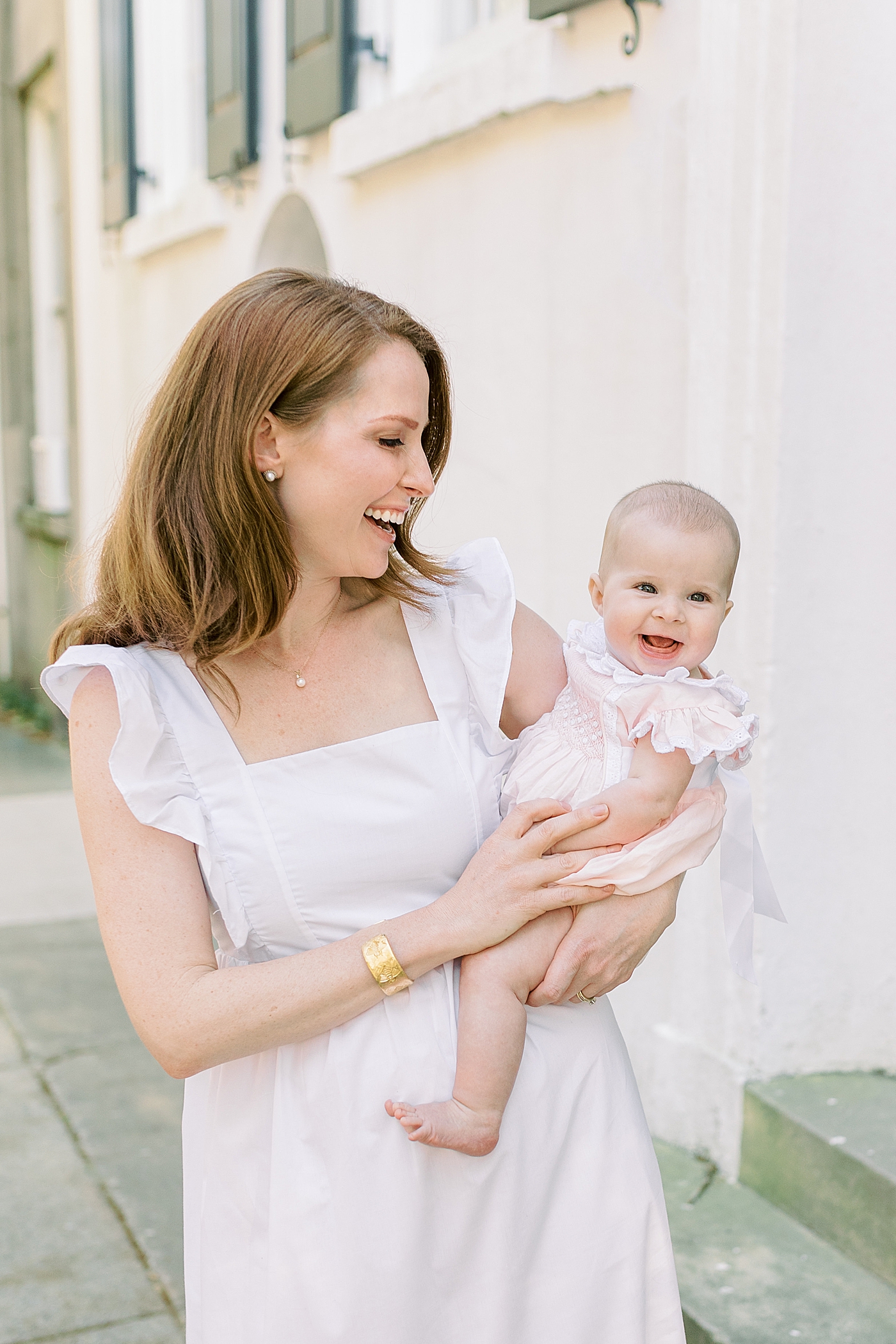 Mother in a spring dress holding her baby during Spring Motherhood Minis in Charleston | Image by Caitlyn Motycka