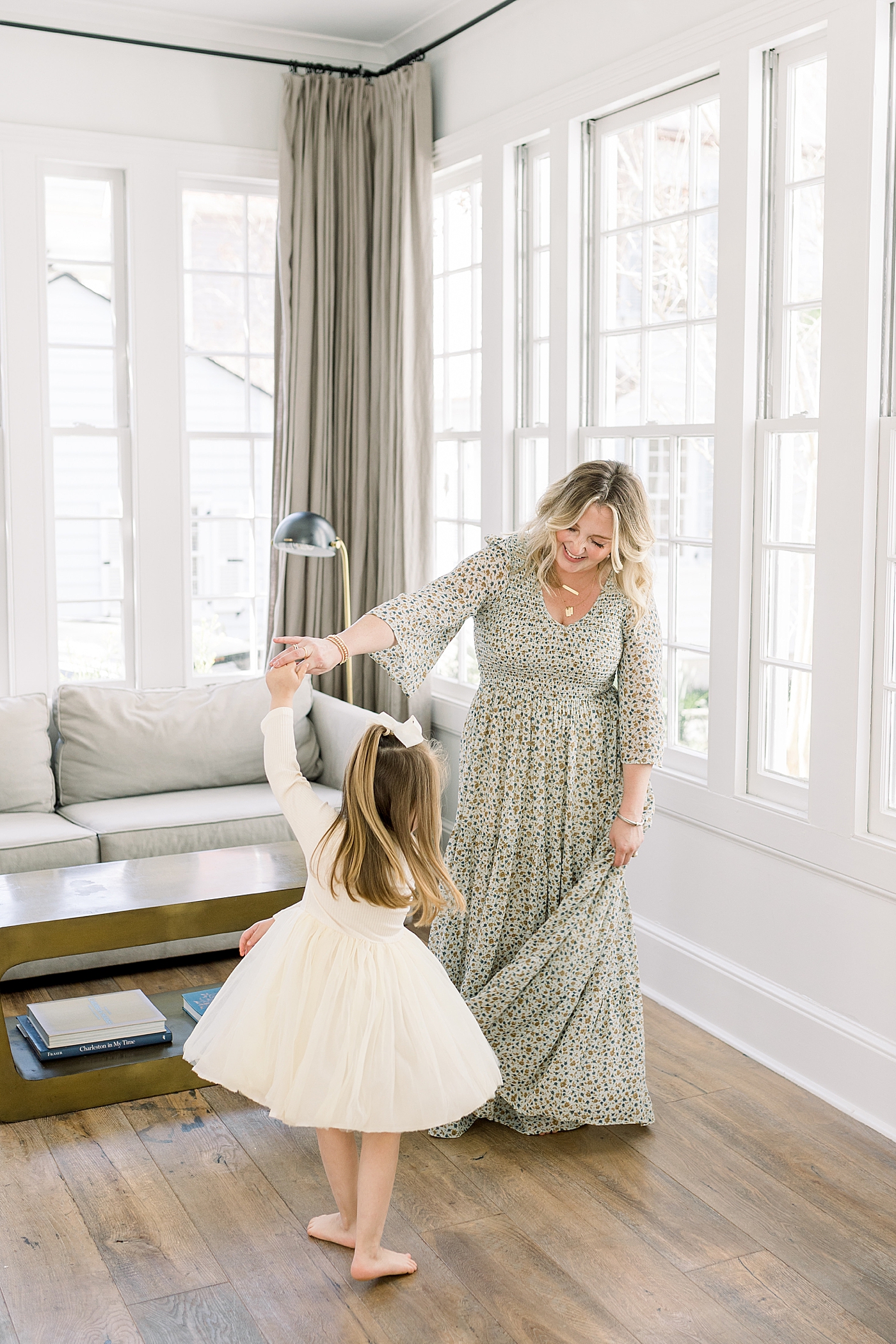 Mom and daughter dancing in their sunny, lit living room | Image by Caitlyn Motycka 