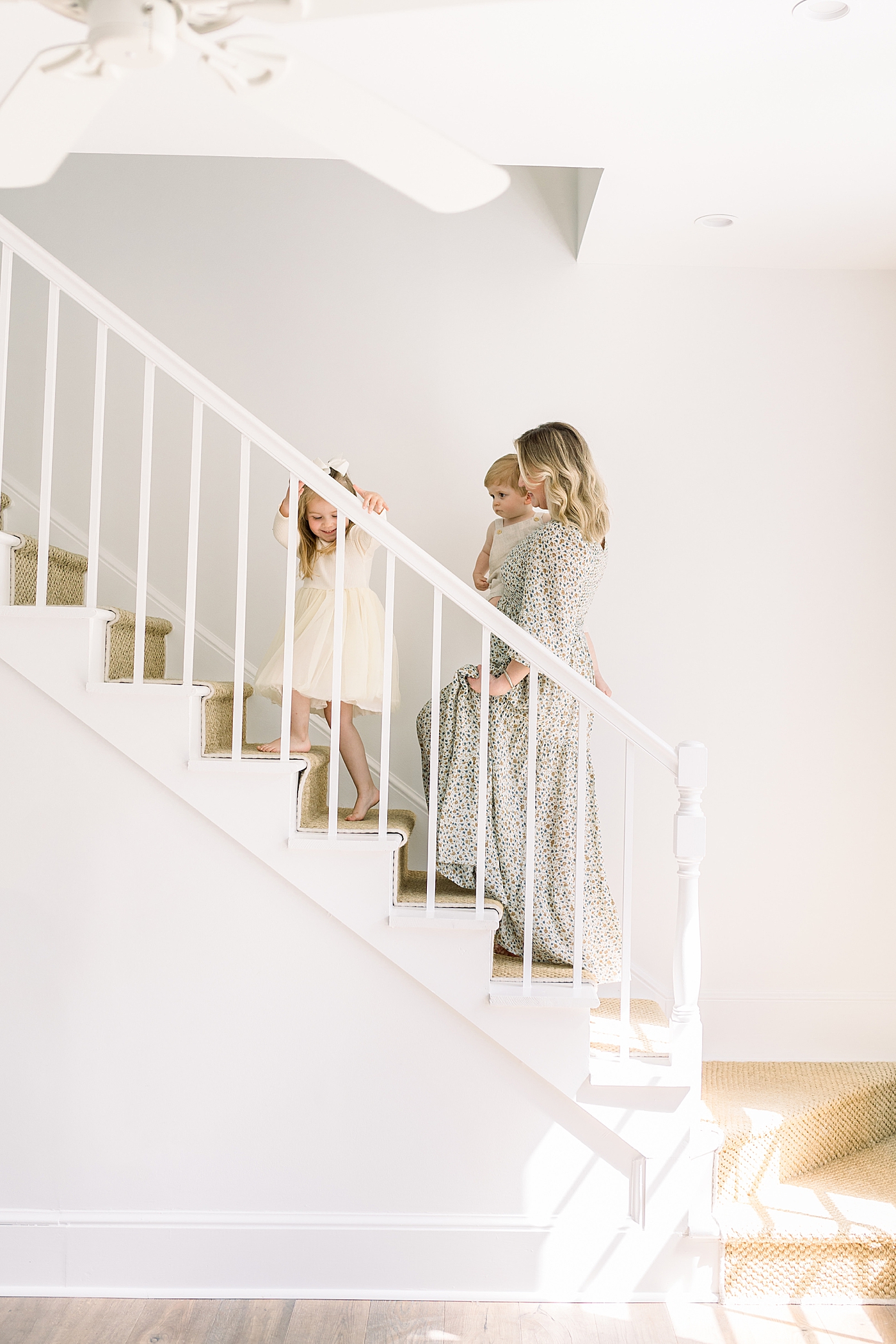 Mother walking up the stairs in her home with her two children | Image by Caitlyn Motycka 