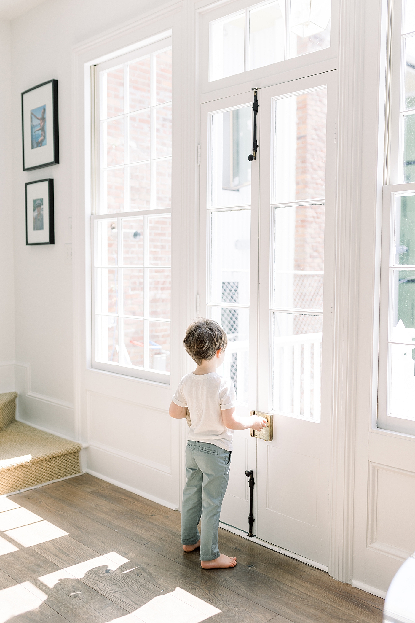 Young boy, barefoot looking out a glass door on a sunny day | Image by Caitlyn Motycka 