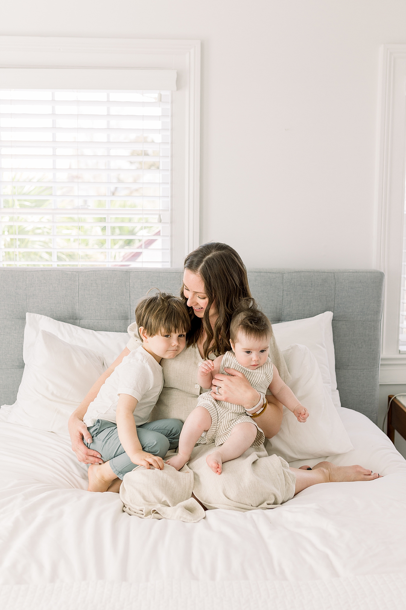 Mother sitting up in bed holding her two children | Image by Caitlyn Motycka 