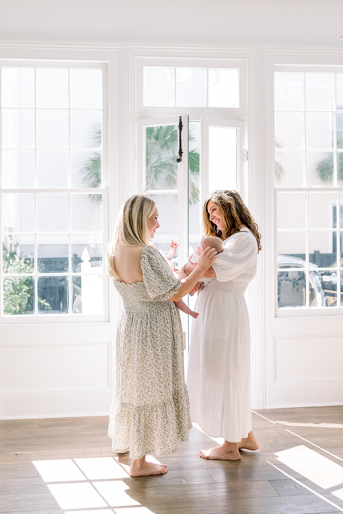 View from behind of a mother and grandmother in spring dresses holding twins | Image by Caitlyn Motycka 