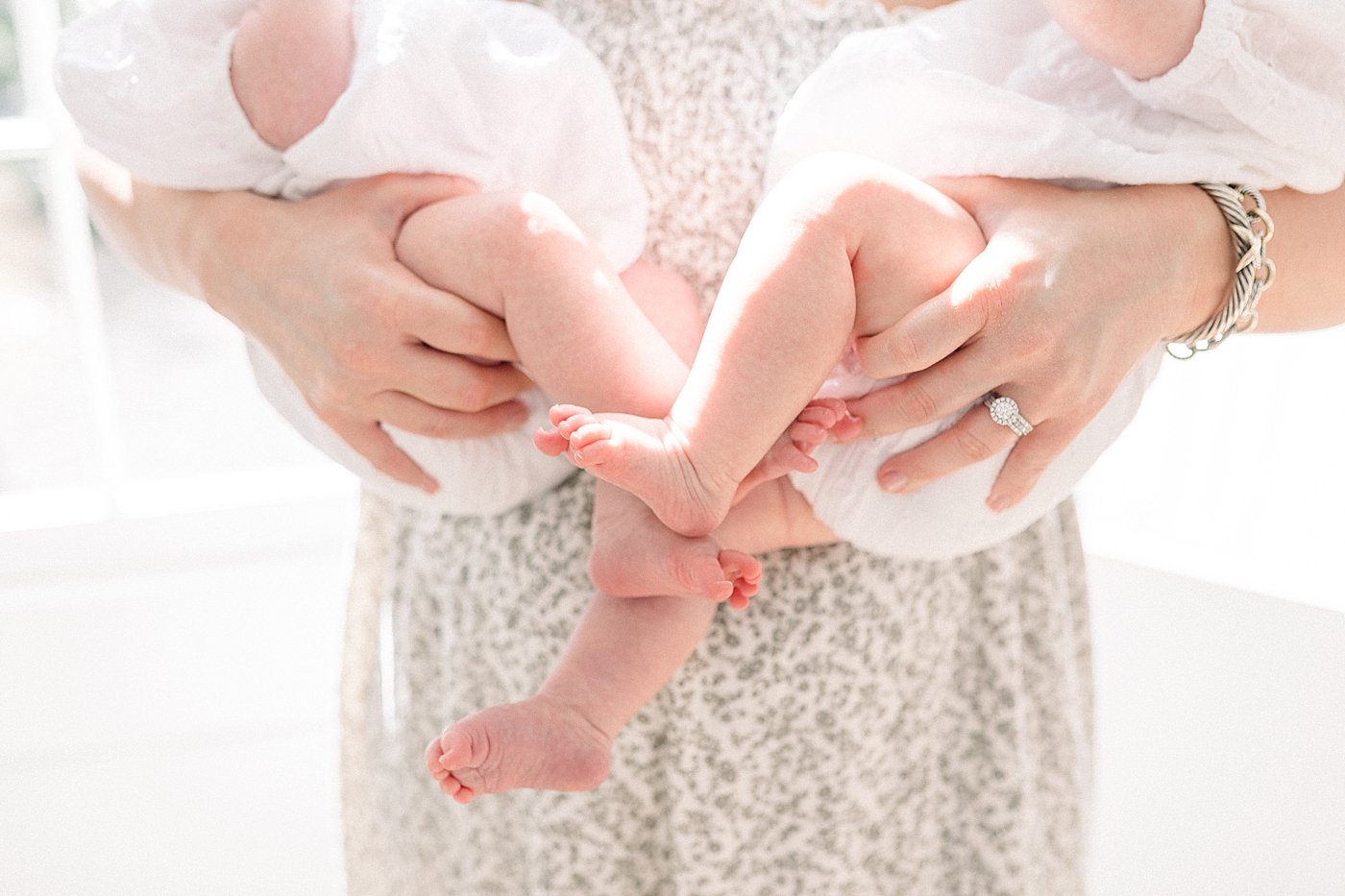 Close up of a mother in a spring dress holding twins with a neutral color palette | Image by Caitlyn Motycka 