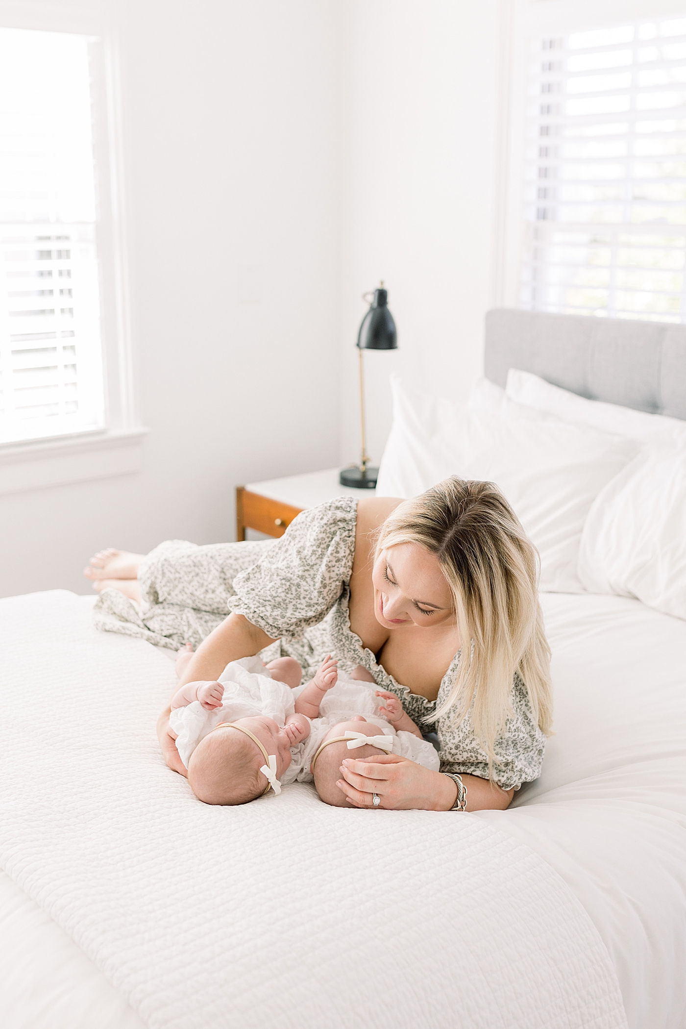 Mother in a spring dress holding twins on a bed with a neutral color palette | Image by Caitlyn Motycka 